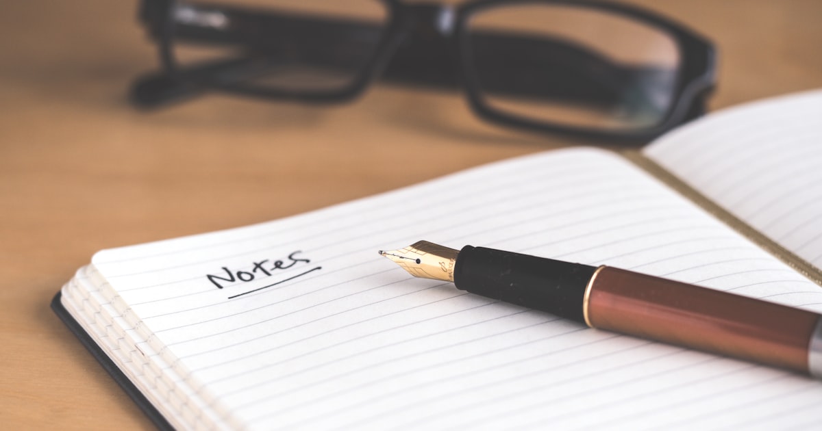 Open journal with handwritten notes beside craft supplies and photographs